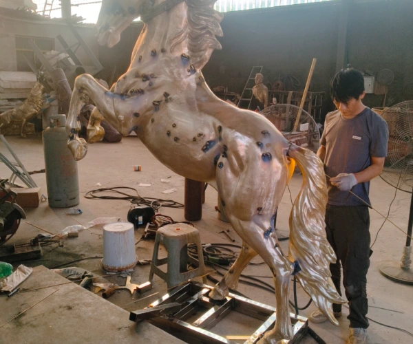 A master sculptor at Yun Sculpture refining the newly assembled bronze horse sculpture after casting and welding.