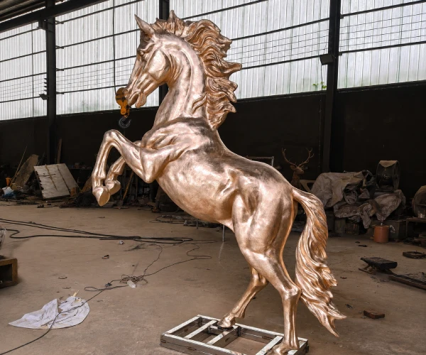 Side view of the rearing bronze horse sculpture before patina, showing the body proportions, raised front legs and flowing mane.