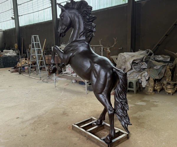 Rear three-quarter view of the finished rearing bronze horse sculpture during final inspection before export packing.