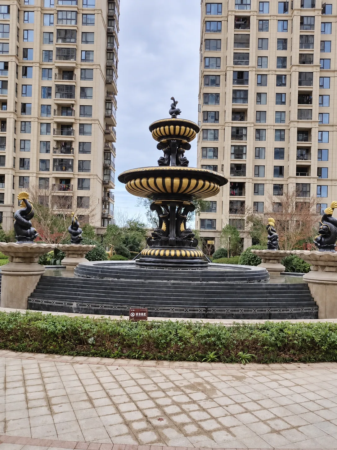 Black and gold two-tier bronze fountain at a residential estate, photographed before water operation