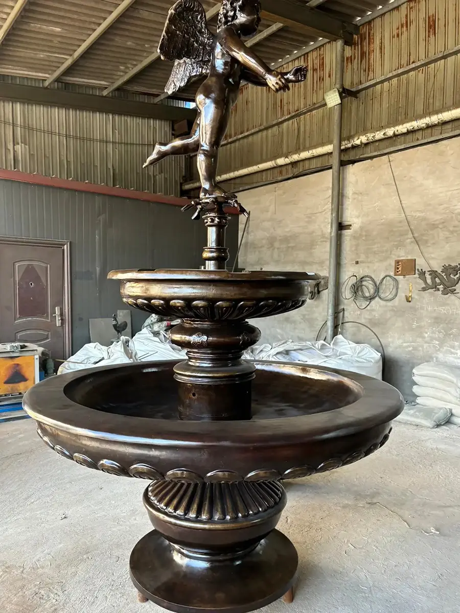 Side view of a bronze angel two-bowl fountain in the workshop