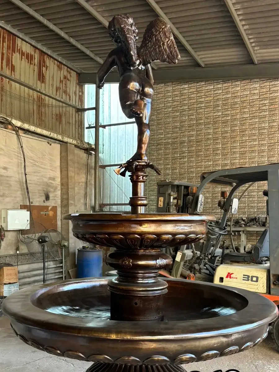 Front view of a bronze angel two-bowl fountain in the workshop