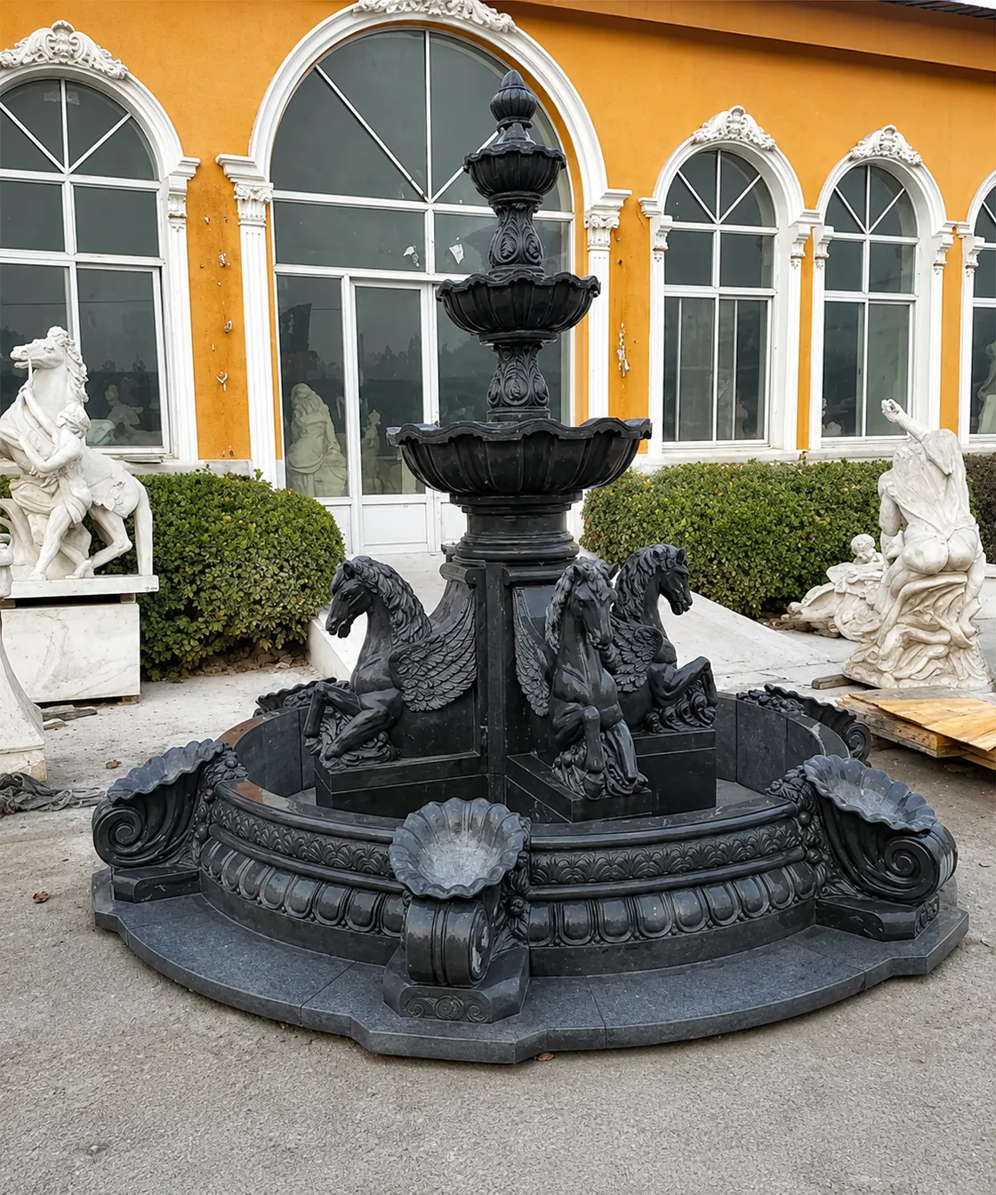 Dark stone tiered fountain with horse figures around its lower section