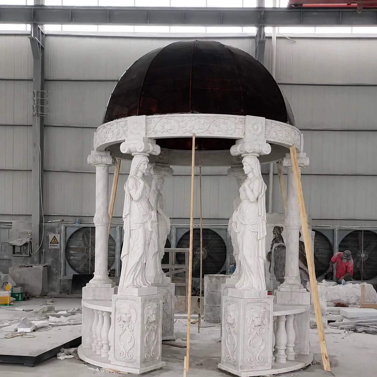 Marble caryatid gazebo with a dark covered dome during factory pre-assembly