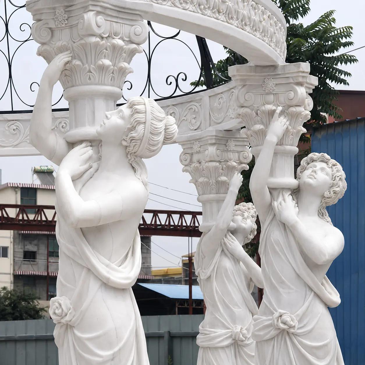 Close view of hand-carved marble female figure columns beneath a metal dome