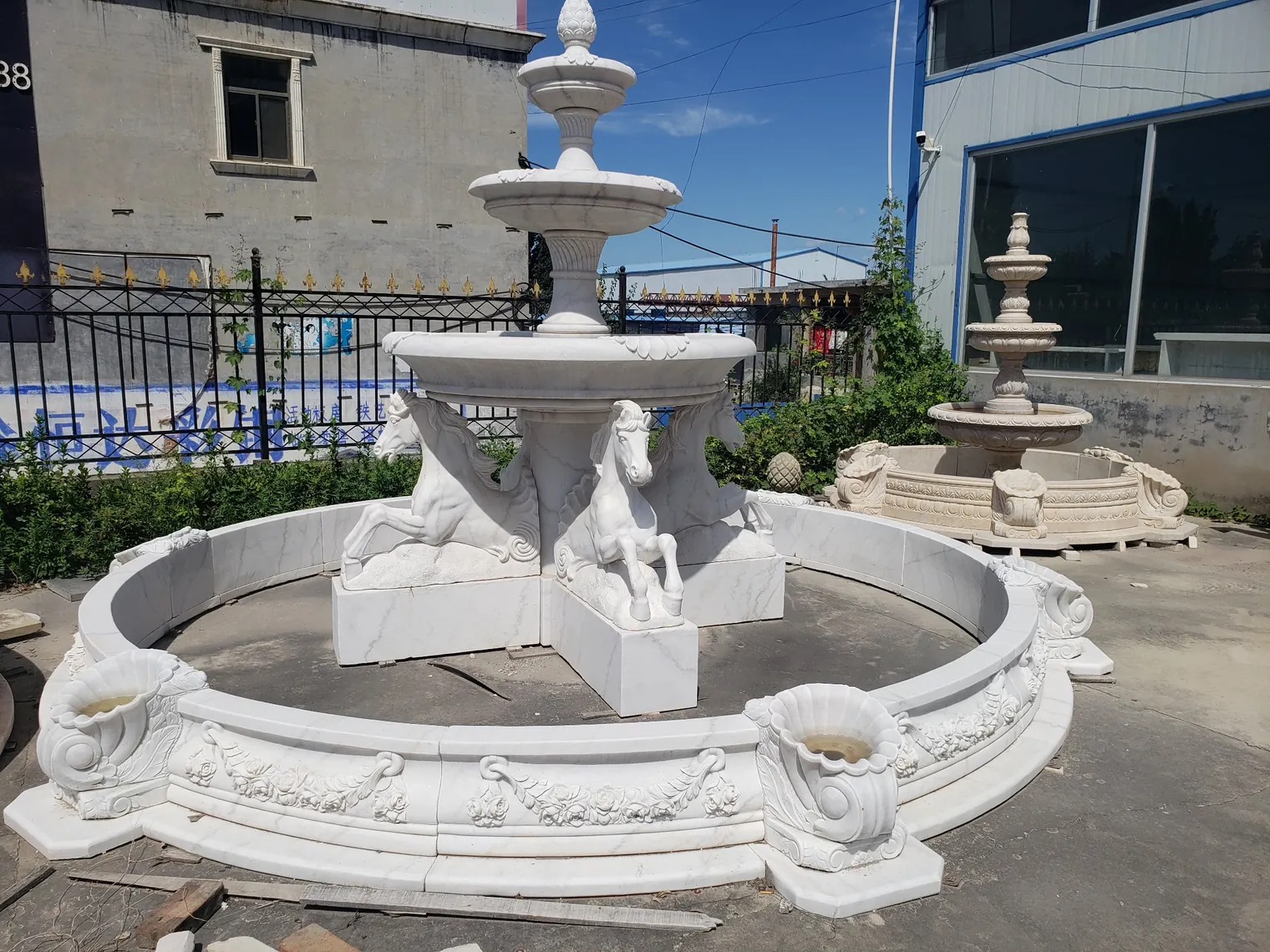 Carved white marble horse tiered fountain with circular stone basin at the workshop