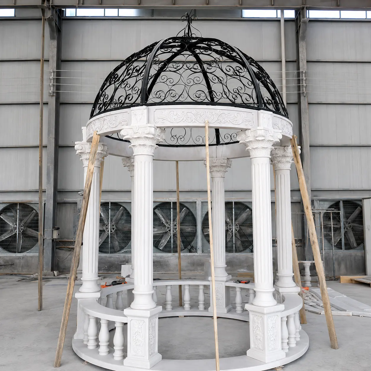 Round white marble gazebo with a black wrought iron birdcage dome in the workshop
