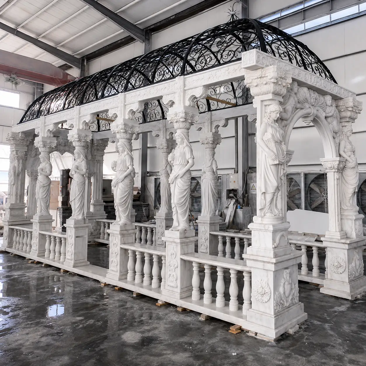 Rectangular stone pavilion with female figure supports and an open ornamental metal canopy in a workshop