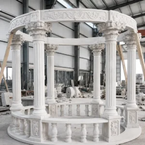 Round stone gazebo with fluted columns, a carved circular upper band and curved balustrade in a workshop