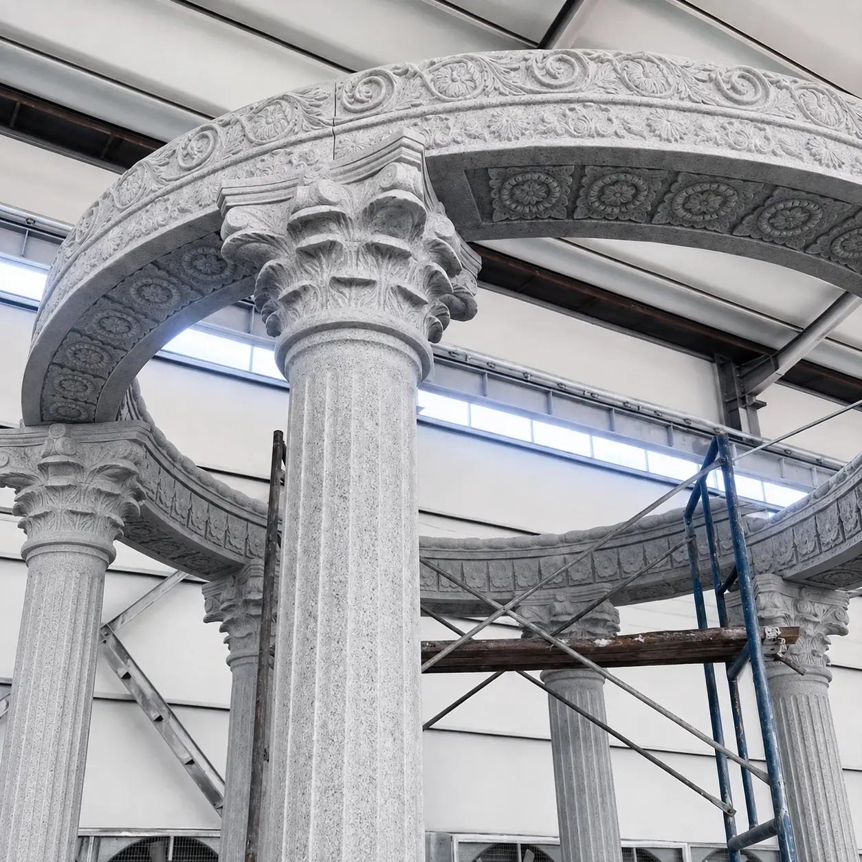 Leaf-carved stone capital, fluted shaft and decorated curved frieze in a workshop