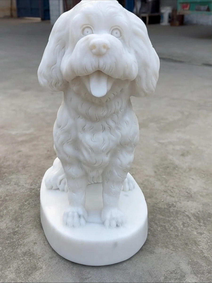 Front view of a white marble seated curly-coated dog sculpture with an open mouth and round integral base in the workshop.