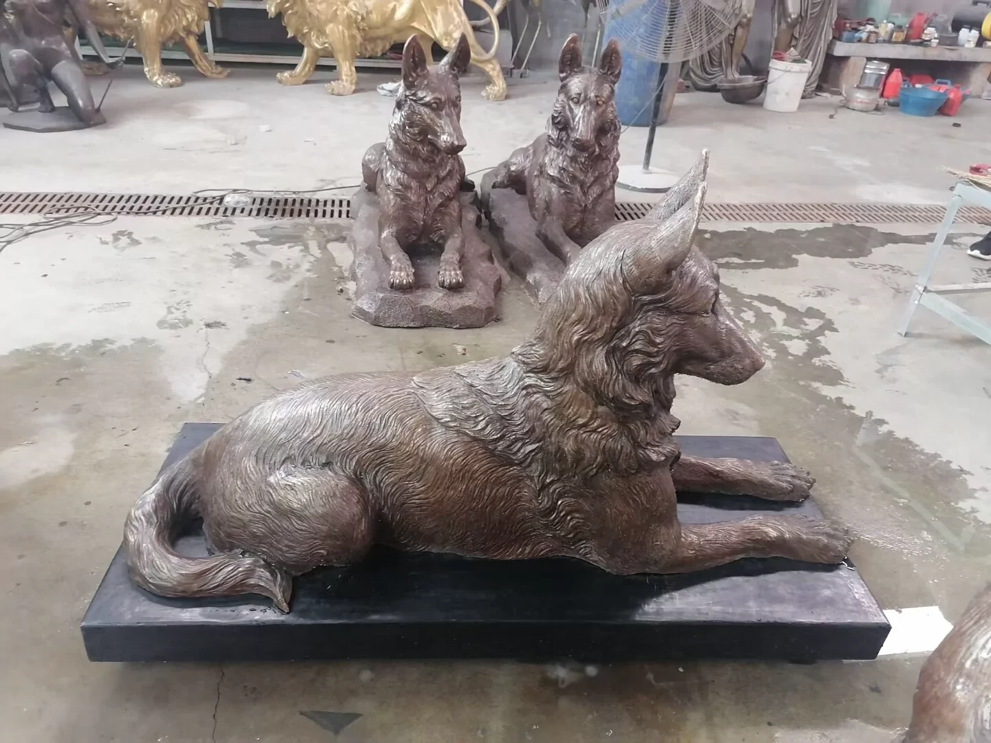 Factory side-view photograph showing the silhouette of a reclining German Shepherd sculpture